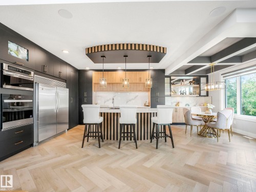 Kitchen featuring appliances with stainless steel finishes, backsplash, light countertops, a breakfast bar area, and pendant lighting - 15 Elwyck Gate, Spruce Grove, AB - Indoor