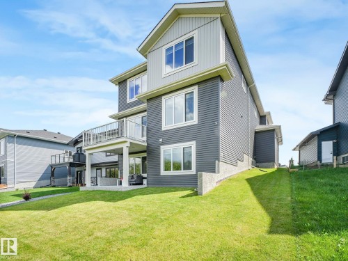 Back of house with a balcony, a lawn, a patio area, and board and batten siding - 15 Elwyck Gate, Spruce Grove, AB - Outdoor