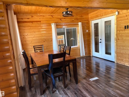 Dining space with french doors, dark wood-style floors, wooden walls, and beam ceiling - B58018 Hiway 29, Rural St. Paul County, AB - Indoor Photo Showing Dining Room