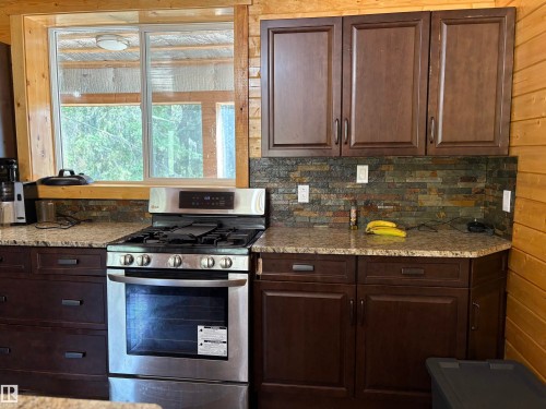 Kitchen featuring gas stove, dark brown cabinetry, and tasteful backsplash - B58018 Hiway 29, Rural St. Paul County, AB - Indoor Photo Showing Kitchen
