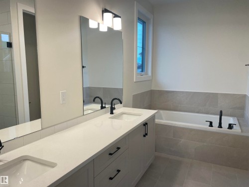 Full bath featuring a bath and double vanity - 4112 Ginsburg Place, Edmonton, AB - Indoor Photo Showing Bathroom