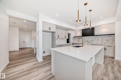 Kitchen with decorative backsplash, light wood-style flooring, light countertops, a spacious island, and pendant lighting - 1401 Ainslie Wynd, Edmonton, AB - Indoor Photo Showing Kitchen With Upgraded Kitchen