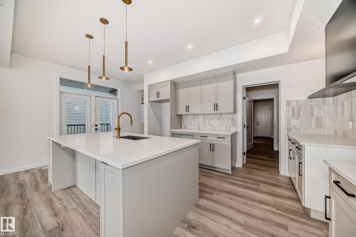 Kitchen featuring tasteful backsplash, light wood-type flooring, a center island with sink, light countertops, and recessed lighting - 1401 Ainslie Wynd, Edmonton, AB - Indoor Photo Showing Kitchen With Upgraded Kitchen