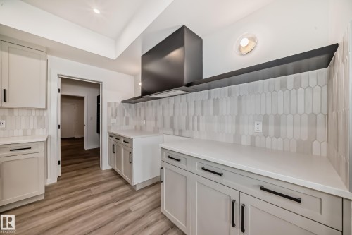 Kitchen featuring decorative backsplash, light wood-style floors, and light countertops - 1401 Ainslie Wynd, Edmonton, AB - Indoor
