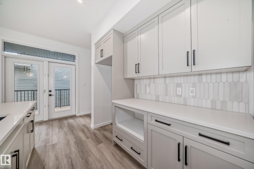 Kitchen with light countertops, light wood-style floors, and backsplash - 1401 Ainslie Wynd, Edmonton, AB - Indoor Photo Showing Kitchen