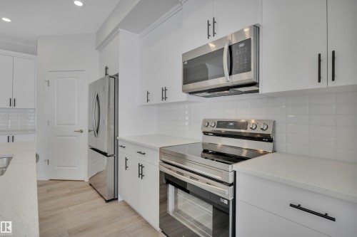 Kitchen with stainless steel appliances, tasteful backsplash, white cabinets, light stone countertops, and recessed lighting - 2275 Alces Drive, Edmonton, AB - Indoor Photo Showing Kitchen With Upgraded Kitchen
