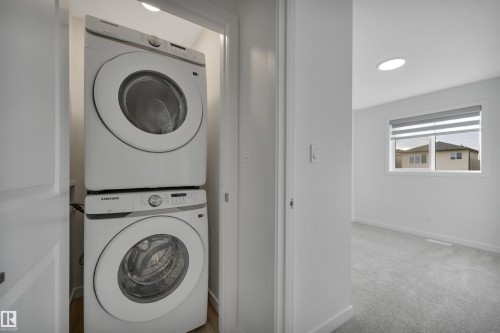 Laundry room with estacked washer and dryer, light carpet, and recessed lighting - 2275 Alces Drive, Edmonton, AB - Indoor Photo Showing Laundry Room