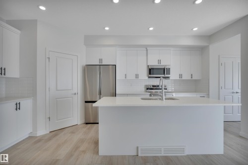 Kitchen with tasteful backsplash, white cabinetry, stainless steel appliances, recessed lighting, and light stone countertops - 2275 Alces Drive, Edmonton, AB - Indoor Photo Showing Kitchen With Upgraded Kitchen