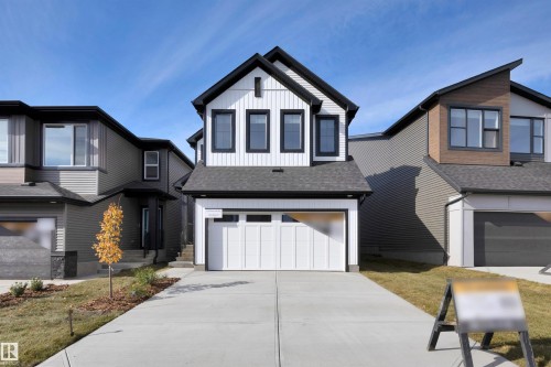 View of front of home featuring board and batten siding, roof with shingles, an attached garage, and concrete driveway - 9104 Elves Loop, Edmonton, AB - Outdoor With Facade