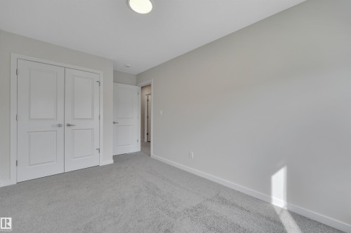 Unfurnished bedroom with a closet and carpet flooring - 9104 Elves Loop, Edmonton, AB - Indoor Photo Showing Other Room