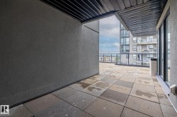 Empty room with a textured wall, floor to ceiling windows, and stone tile flooring - 