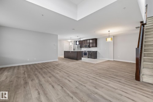 Unfurnished living room with light wood finished floors and stairs - 810 5151 Windermere Boulevard, Edmonton, AB - Indoor