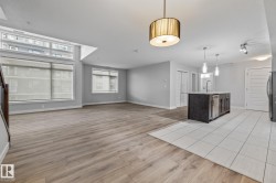 Kitchen featuring light wood-type flooring, light countertops, open floor plan, and hanging light fixtures - 