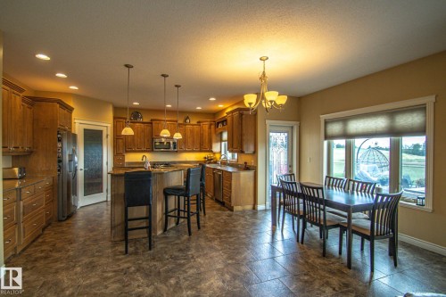 Kitchen with a kitchen bar, a kitchen island with sink, brown cabinetry, recessed lighting, and a chandelier - 5753 43 Ave, St. Paul Town, AB - Indoor Photo Showing Other Room