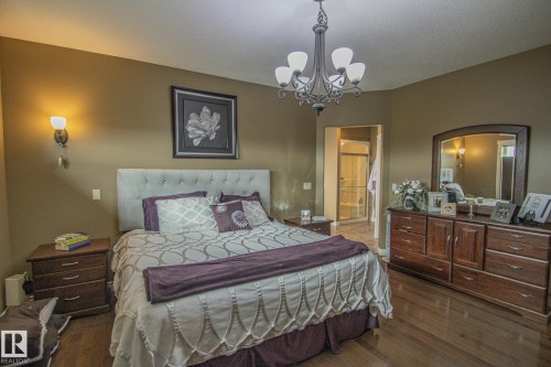Bedroom with a chandelier, dark wood-style floors, and connected bathroom - 5753 43 Ave, St. Paul Town, AB - Indoor Photo Showing Bedroom