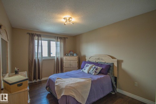 Bedroom with dark wood-style flooring and a textured ceiling - 5753 43 Ave, St. Paul Town, AB - Indoor Photo Showing Bedroom