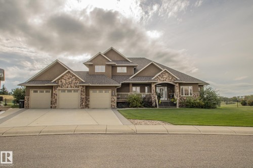 Craftsman inspired home with a front yard, covered porch, a garage, driveway, and stone siding - 5753 43 Ave, St. Paul Town, AB - Outdoor With Facade