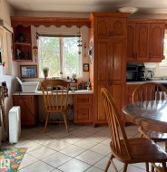 Kitchen featuring light tile patterned flooring, brown cabinetry, a textured ceiling, and built in desk - 