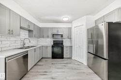 Kitchen with stainless steel appliances, backsplash, gray cabinets, and light wood-style floors - 