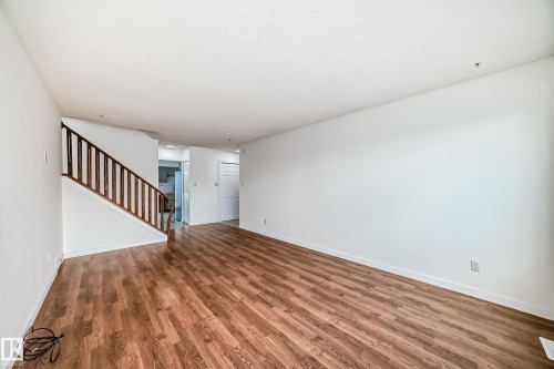 Unfurnished living room with wood finished floors, stairs, and a textured ceiling - 13116 31 Strret, Edmonton, AB - Indoor Photo Showing Other Room