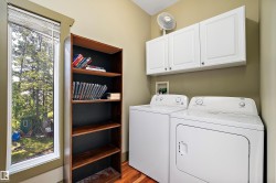 Laundry room featuring light wood finished floors, washer and clothes dryer, and cabinet space - 