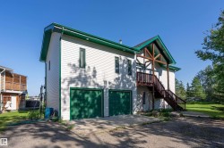 View of property exterior featuring driveway, an attached garage, and stairway - 