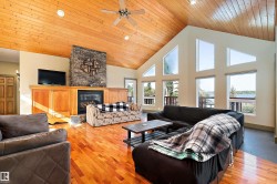Living room with high vaulted ceiling, light wood-style flooring, a fireplace, a ceiling fan, and wood ceiling - 