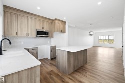 Kitchen with light stone counters, backsplash, a center island, stainless steel microwave, and recessed lighting - 