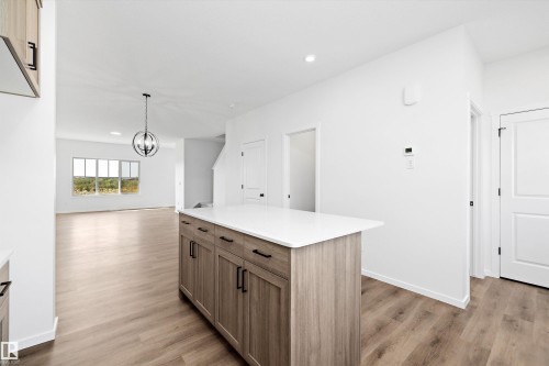 Kitchen with a center island, light wood-style flooring, hanging light fixtures, brown cabinetry, and recessed lighting - 5458 Hawthorn Run, Edmonton, AB - Indoor