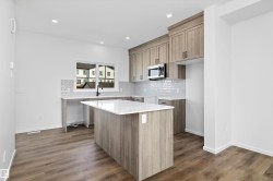 Kitchen featuring tasteful backsplash, light stone counters, recessed lighting, stainless steel microwave, and dark wood-type flooring - 