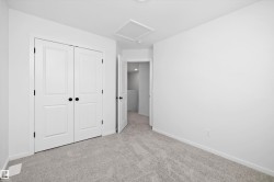 Unfurnished bedroom with light colored carpet, attic access, and a closet - 