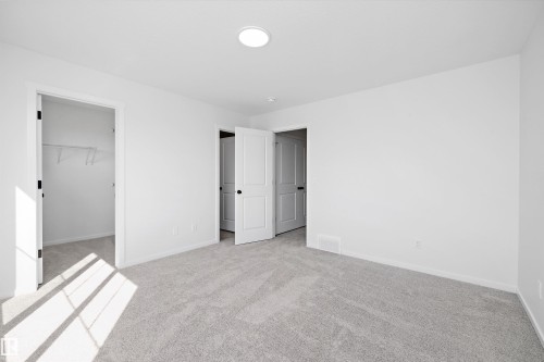 Unfurnished bedroom featuring light carpet and a spacious closet - 5458 Hawthorn Run, Edmonton, AB - Indoor