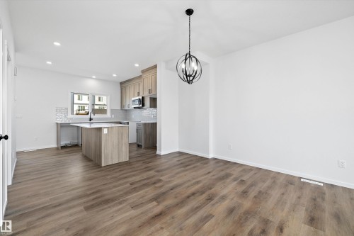 Kitchen with tasteful backsplash, dark wood-style flooring, a chandelier, a kitchen island, and recessed lighting - 5458 Hawthorn Run, Edmonton, AB - Indoor Photo Showing Kitchen