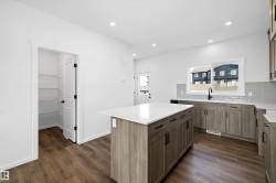 Kitchen featuring decorative backsplash, a center island, recessed lighting, dark wood-type flooring, and light stone counters - 