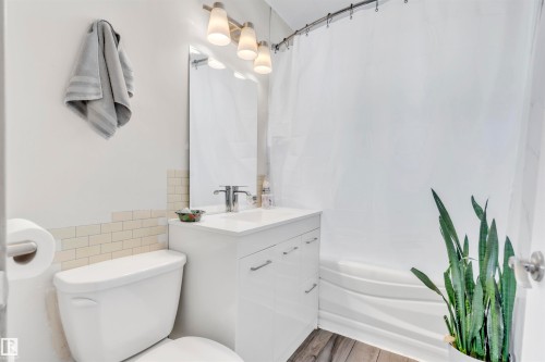 Bathroom featuring shower / bath combination with curtain, vanity, tile walls, and wood finished floors - 4702 50 Avenue, Cold Lake, AB - Indoor Photo Showing Bathroom