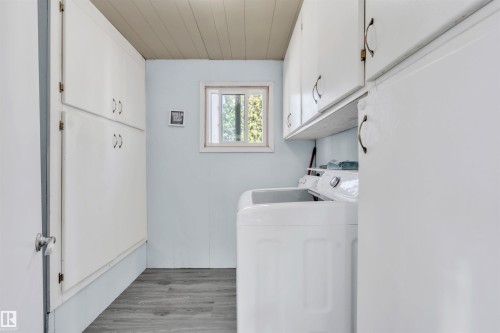 Washroom featuring cabinet space, light wood finished floors, and washing machine and clothes dryer - 4702 50 Avenue, Cold Lake, AB - Indoor Photo Showing Laundry Room