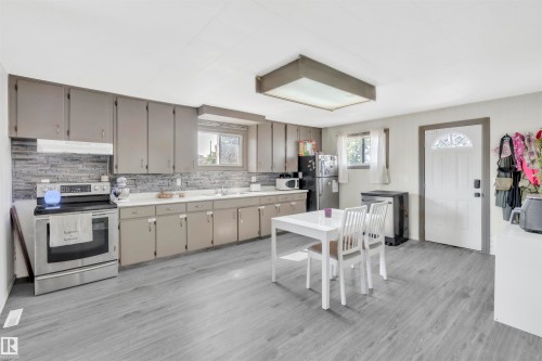 Kitchen featuring stainless steel appliances, decorative backsplash, light countertops, and plenty of natural light - 4702 50 Avenue, Cold Lake, AB - Indoor Photo Showing Kitchen With Double Sink