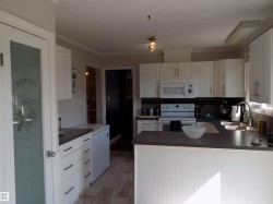 Kitchen featuring dark countertops, white appliances, white cabinetry, tasteful backsplash, and crown molding - 
