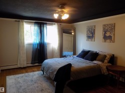Bedroom featuring dark wood-style floors, ceiling fan, a textured ceiling, and a baseboard heating unit - 