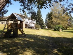 View of green lawn with a playground, stairway, and a wooden deck - 