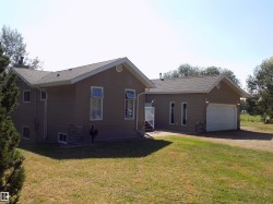View of front of house featuring a front yard, a garage, a shingled roof, and dirt driveway - 