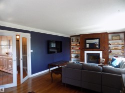 Living room with wood finished floors, a fireplace, a textured ceiling, crown molding, and built in features - 