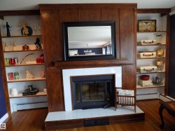 Detailed view of built in shelves, a baseboard radiator, a fireplace, and wood finished floors - 