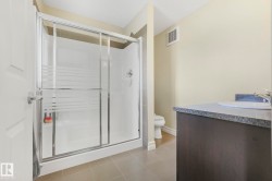 Full bathroom featuring vanity, a shower stall, light tile patterned floors, and a textured ceiling - 