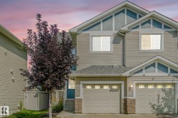 View of front of house with an attached garage, stone siding, and concrete driveway - 