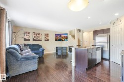 Kitchen featuring dark brown cabinets, open floor plan, appliances with stainless steel finishes, light stone countertops, and dark wood-type flooring - 