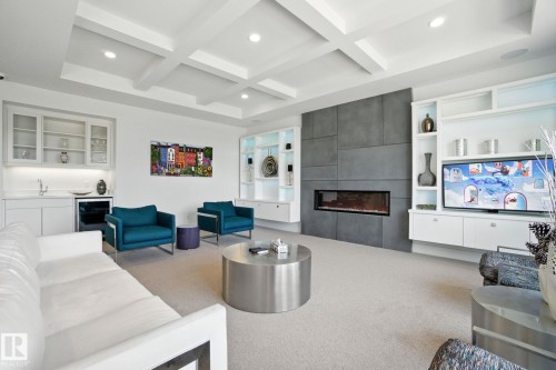 Carpeted living area with a tiled fireplace, wet bar, recessed lighting, beverage cooler, and beam ceiling - 11823 Saskatchewan Drive, Edmonton, AB - Indoor Photo Showing Living Room With Fireplace