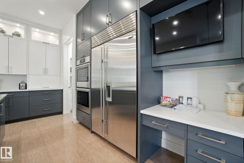 Kitchen with glass insert cabinets, appliances with stainless steel finishes, gray cabinets, light wood-style floors, and light stone countertops - 11823 Saskatchewan Drive, Edmonton, AB - Indoor Photo Showing Kitchen With Upgraded Kitchen