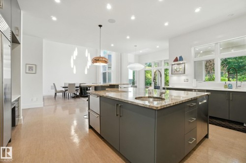 Kitchen featuring recessed lighting, hanging light fixtures, a large island with sink, light stone countertops, and modern cabinets - 11823 Saskatchewan Drive, Edmonton, AB - Indoor Photo Showing Kitchen With Upgraded Kitchen