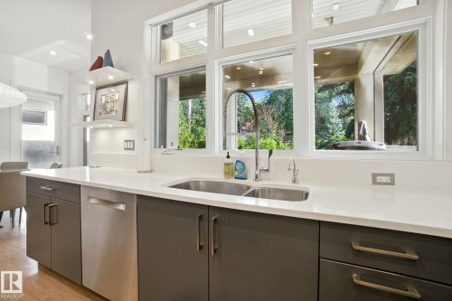 Kitchen featuring stainless steel dishwasher, gray cabinets, and light stone counters - 11823 Saskatchewan Drive, Edmonton, AB - Indoor Photo Showing Kitchen With Double Sink
